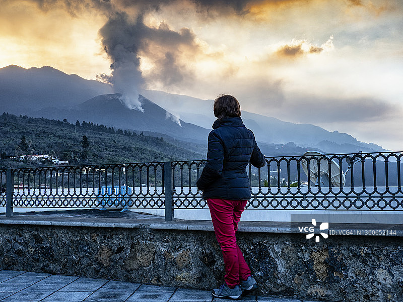妇女沉思火山爆发，老峰火山主锥喷出烟柱和熔岩图片素材