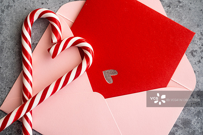 粉色信封、红色明信片和心形拐杖糖特写，情人节贺卡俯视图图片素材