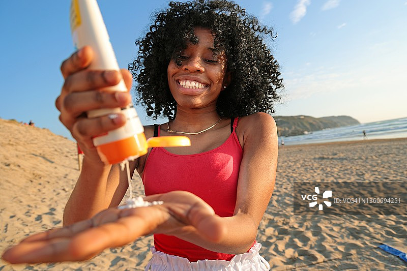 在沙滩上挤防晒霜的年轻女人图片素材