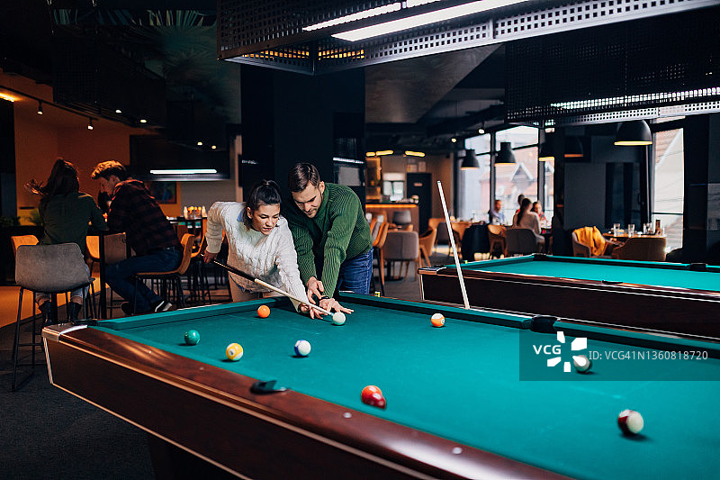 女人移动中，男友教她如何打台球图片素材