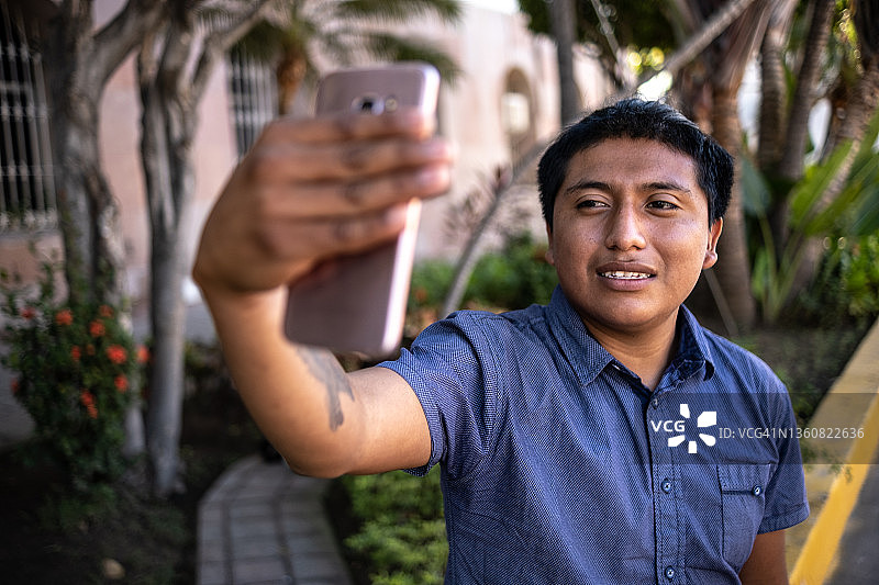 年轻男人在户外用手机自拍或拍摄图片素材