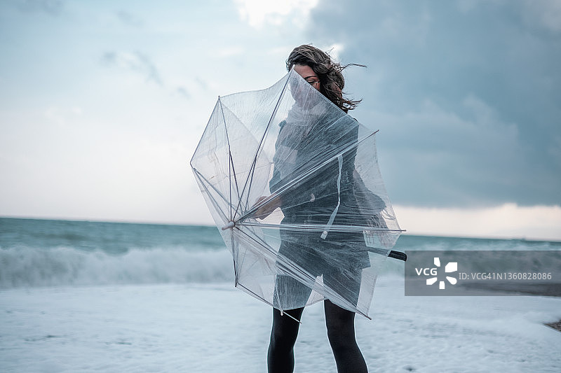 在雨中独自走在海滩上的悲伤年轻女子图片素材