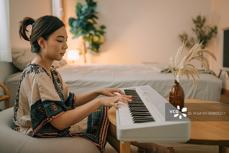 在家练习钢琴的年轻女人图片素材
