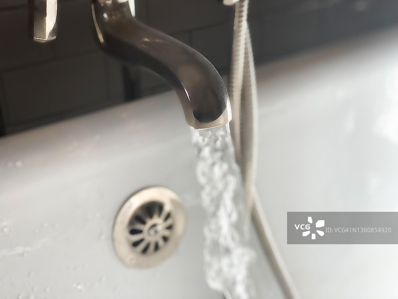 老式抛光镍十字把手浴缸水龙头和手持喷雾器流水图片素材