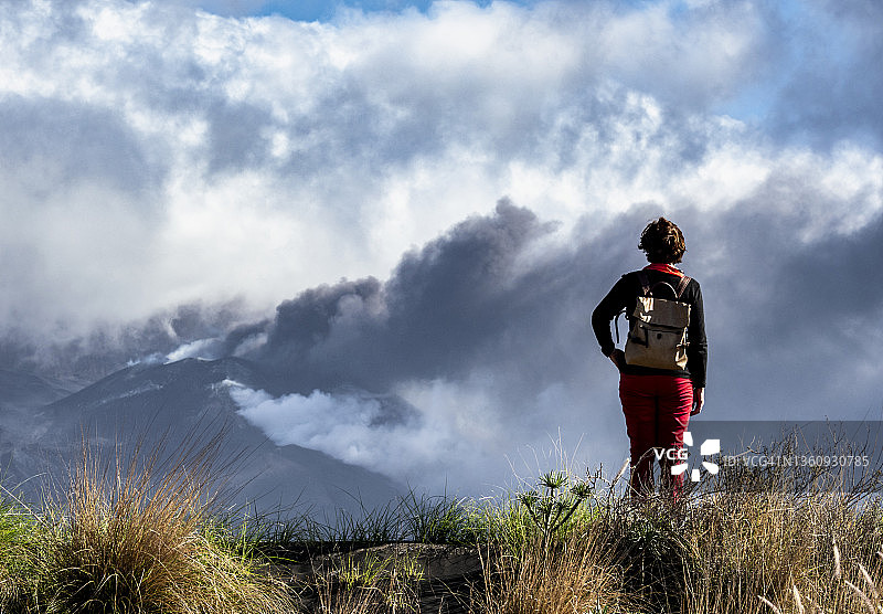 妇女沉思火山爆发，老峰火山主锥喷出烟柱和熔岩图片素材