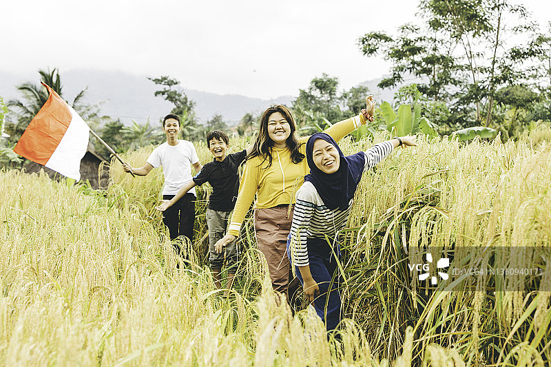 穆斯林妇女与她的兄弟和朋友在村庄里拿着印度尼西亚国旗图片素材