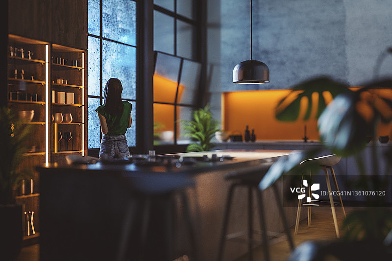 雨夜，年轻女子在厨房窗口向外看图片素材