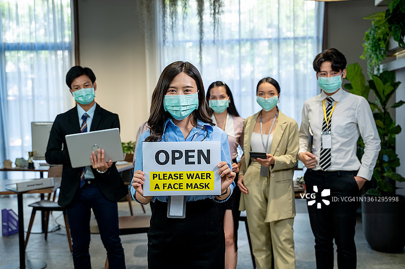 戴防护口罩的办公室职员，共同克服疫情以重新开展业务图片素材