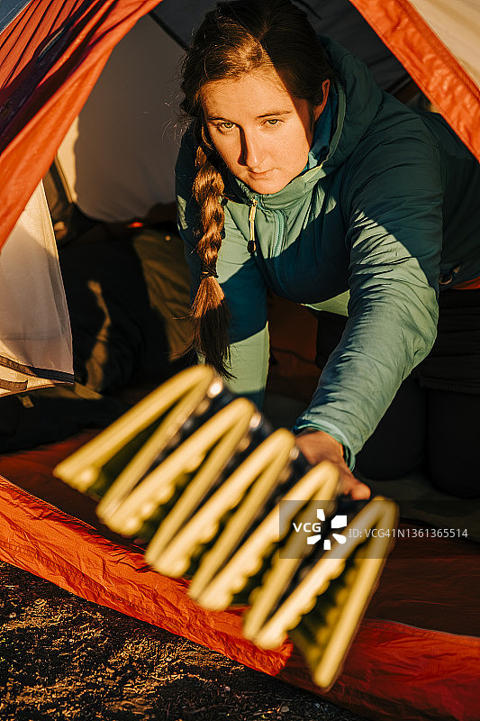 女露营者收拾泡沫床垫并从帐篷里递出图片素材