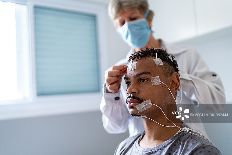 医生在病人头部放置电极进行多导睡眠监测图片素材