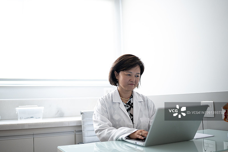 医生在医疗诊所操作笔记本电脑。图片素材