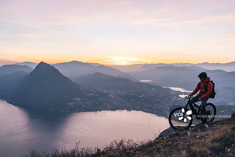 山地自行车手在日出时分于山脊上放松图片素材