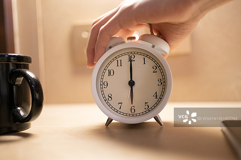 躺在床上，手里拿着闹钟的亚洲男人图片素材