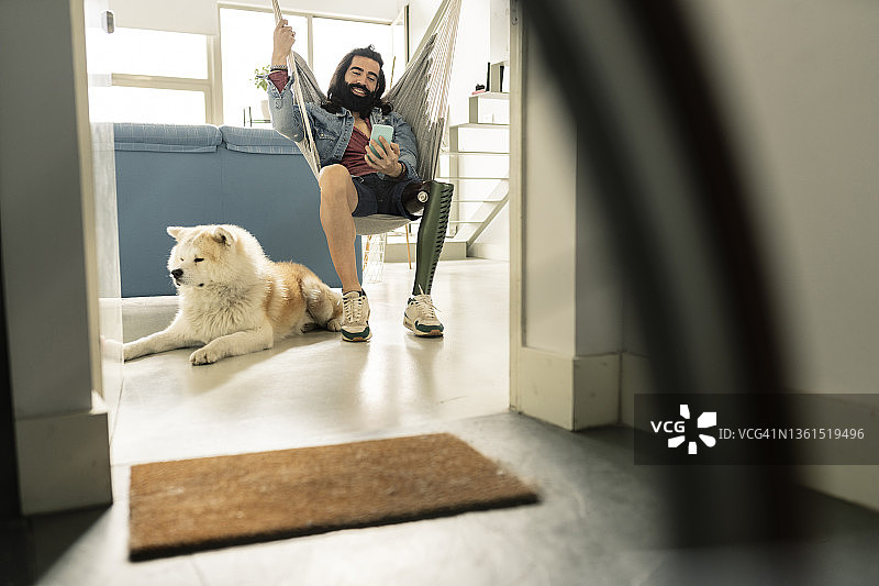 在家中带着腿部假肢和他的狗的男人图片素材