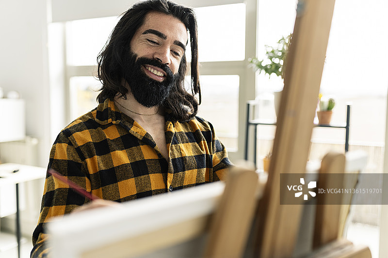 英俊的胡须男人在家画画图片素材