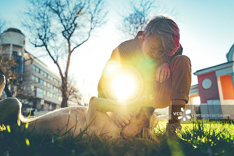 阳光下与小狗玩耍的年轻英俊男子图片素材
