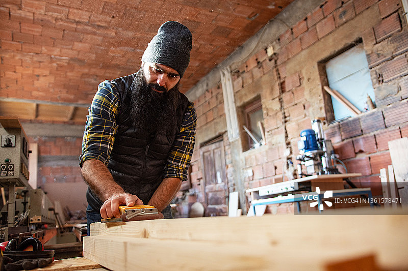 年轻的木匠在他的车间里工作图片素材