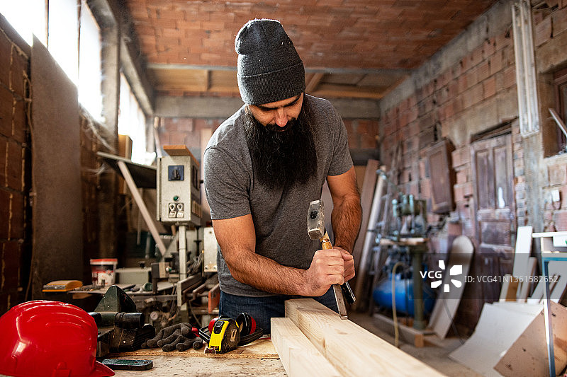 在修理车间使用锤子和凿子的年轻男人图片素材