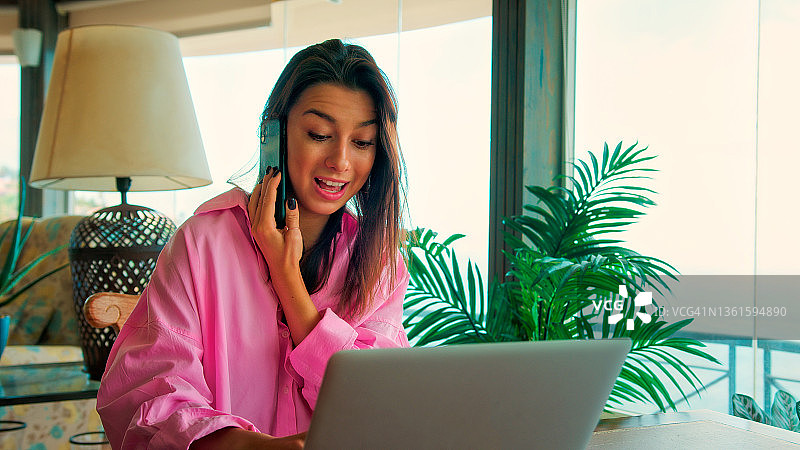 在全景窗边工作的女人。使用笔记本电脑，一边喝咖啡一边欣赏壮丽的海景图片素材