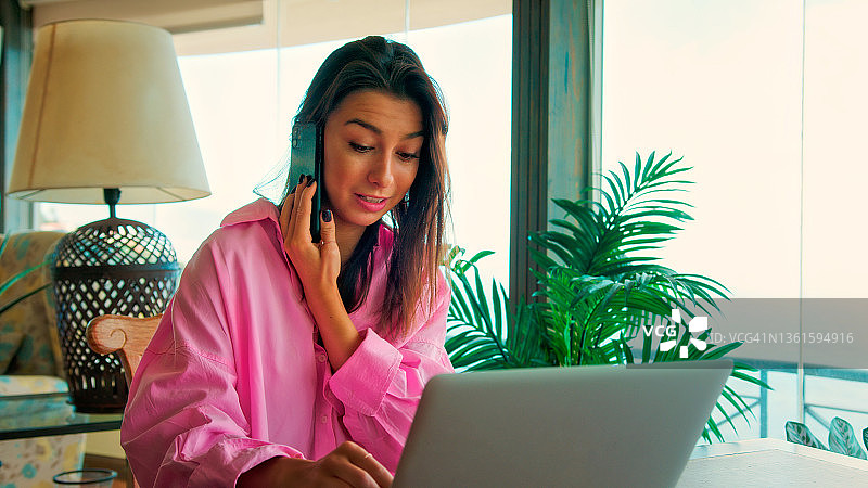 在全景窗边工作的女人。使用笔记本电脑，一边喝咖啡一边欣赏壮丽的海景图片素材