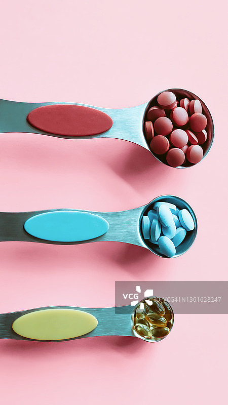 粉色背景上量匙中的药丸图片素材