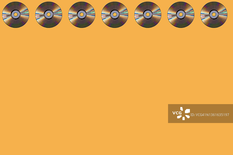 黄色背景上的银色CD光盘图案图片素材