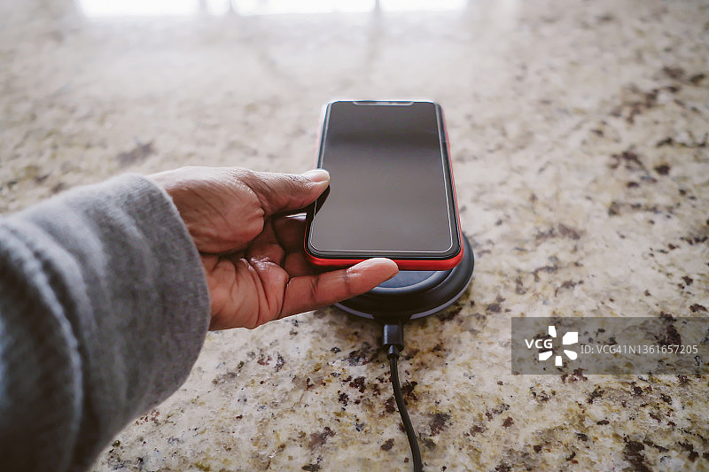 女人将智能手机放在无线充电器上图片素材