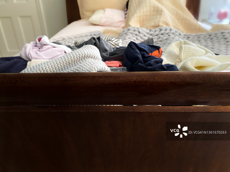 躺在床上，床脚堆满干净衣物的少女图片素材