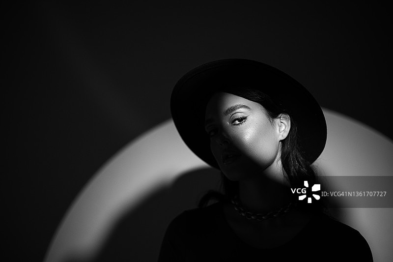戴圆帽的年轻漂亮女人肖像（面部有阴影）图片素材