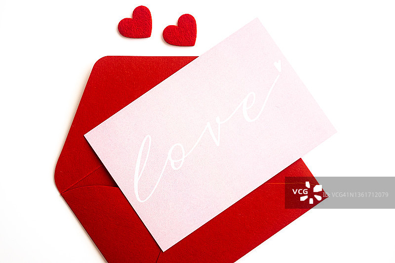 白色背景上的红色信封和爱心明信片特写，顶部视角，情人节贺卡图片素材