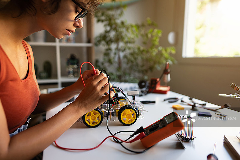 女性机器人工程师用万用表读取自动驾驶原型车的电压图片素材