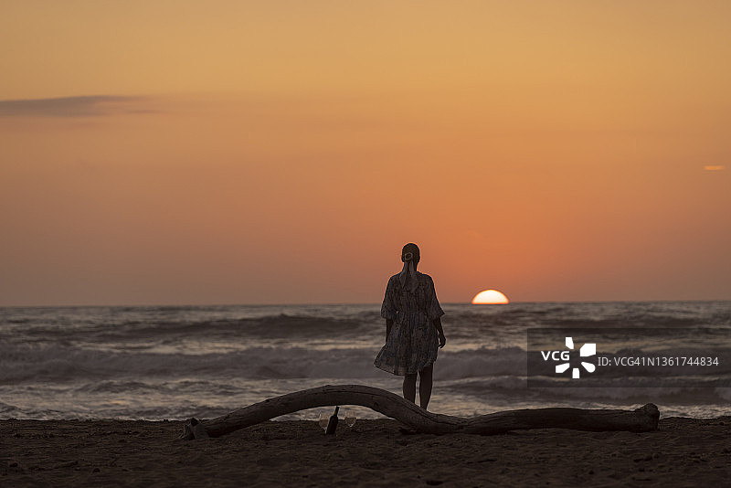 日落时分在海滩上的沮丧女人，意大利撒丁岛。图片素材