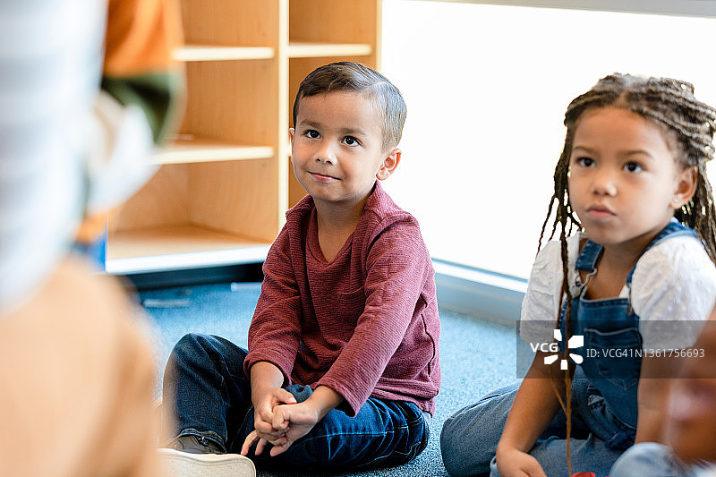 专注的小男孩听着幼儿园老师讲课图片素材