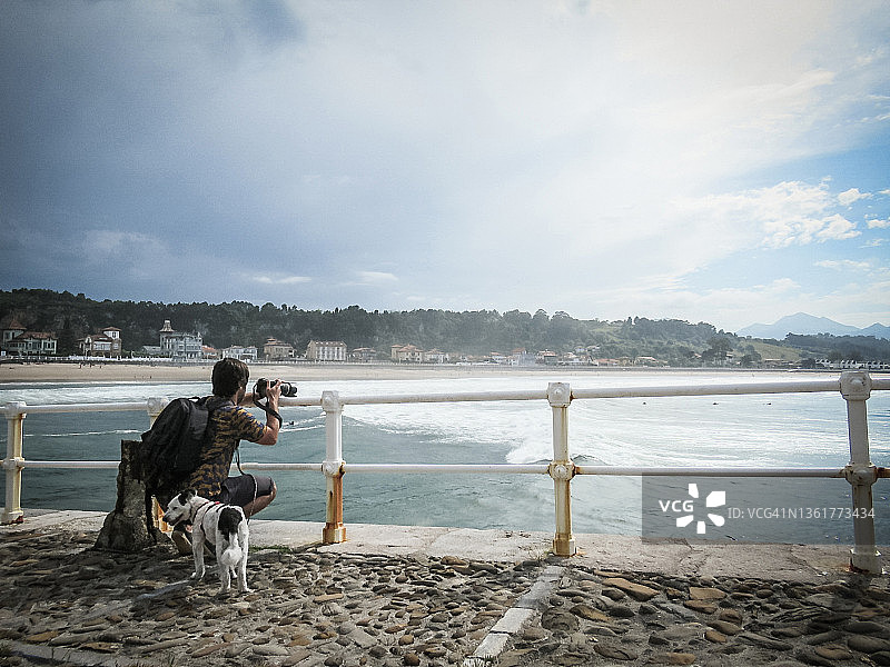 摄影师在阳光明媚的海岸拍摄图片素材