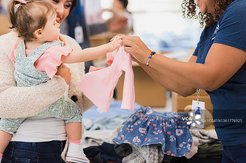 慈善商店志愿者向女孩提供连衣裙（未识别人物）图片素材