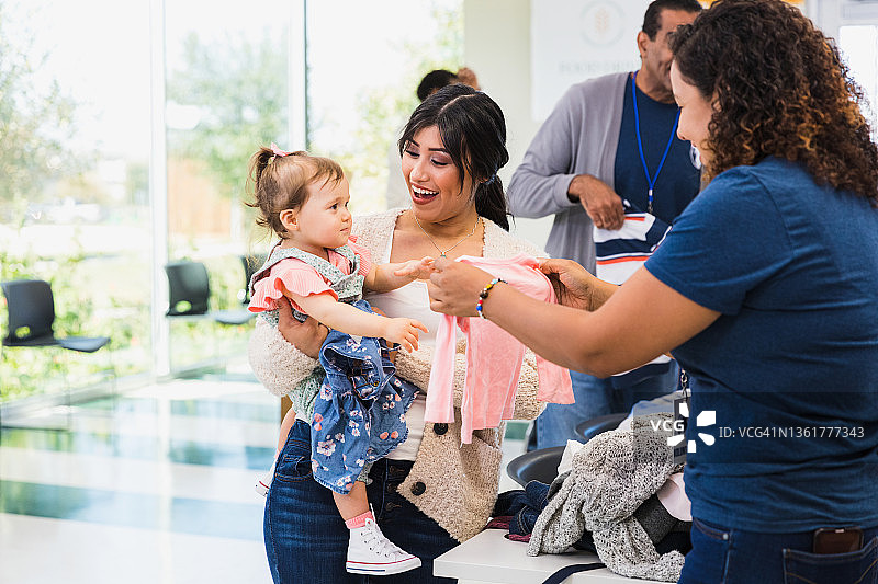 服装捐赠志愿者协助年轻女人挑选服装图片素材