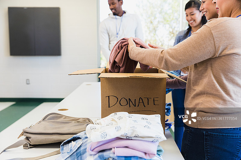 志愿者在慈善活动中从箱子中取出捐赠物品图片素材