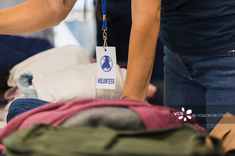 志愿者靠在叠好的衣服堆上图片素材