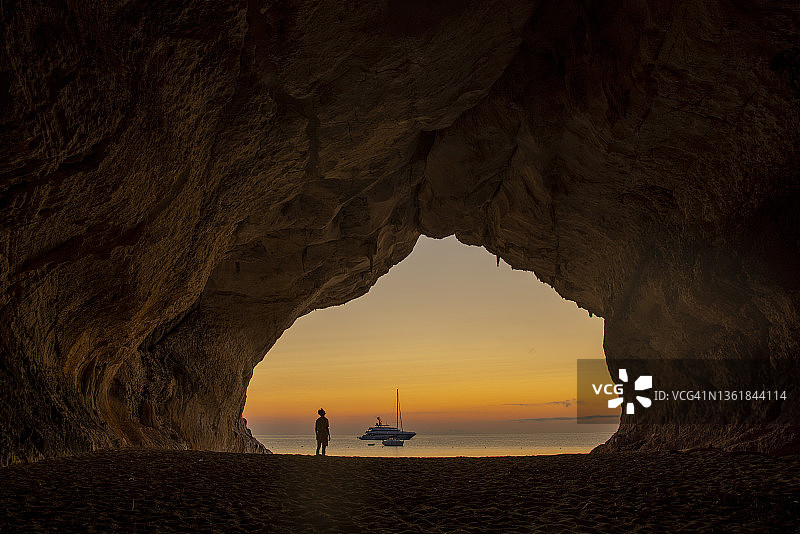 意大利撒丁岛卡拉卢纳洞穴日落时分的海滩上的男人图片素材