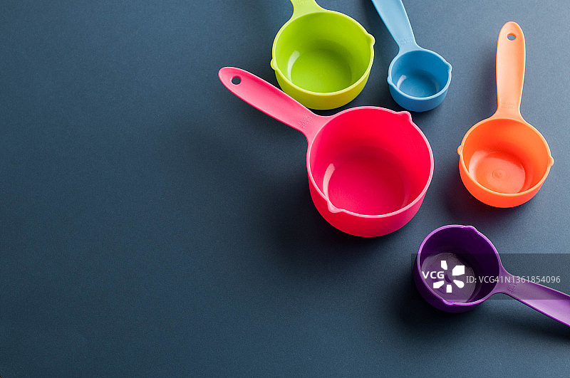 各种彩色量勺在蓝色背景上的金融概念平面图图片素材