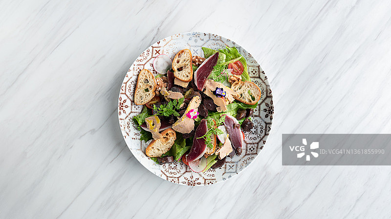 法式沙拉配肉酱、食用鲜花、面包和大理石餐桌装饰图片素材