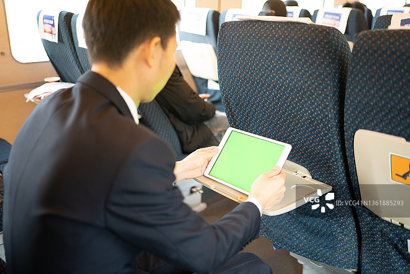 亚洲男人在高铁上使用平板电脑图片素材
