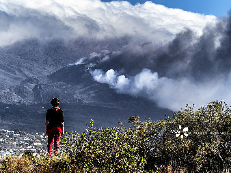 妇女沉思火山爆发，老峰火山主锥喷出烟柱和熔岩图片素材