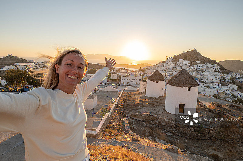 日落山顶女人举臂望希腊小镇图片素材