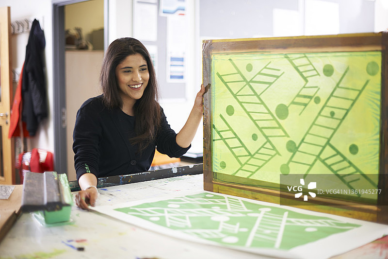微笑的女艺术生在艺术工作室进行丝网印刷图片素材