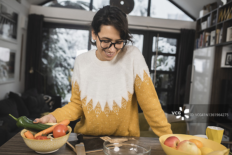 快乐的年轻女人在家准备新鲜蔬菜图片素材