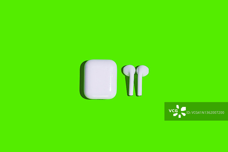 绿色背景上的白色无线耳机图片素材