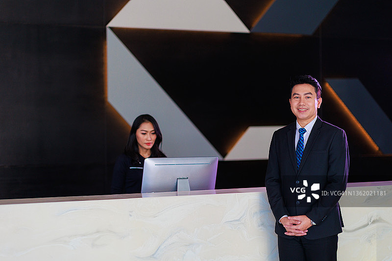 男酒店经理站在大堂接待柜台前图片素材