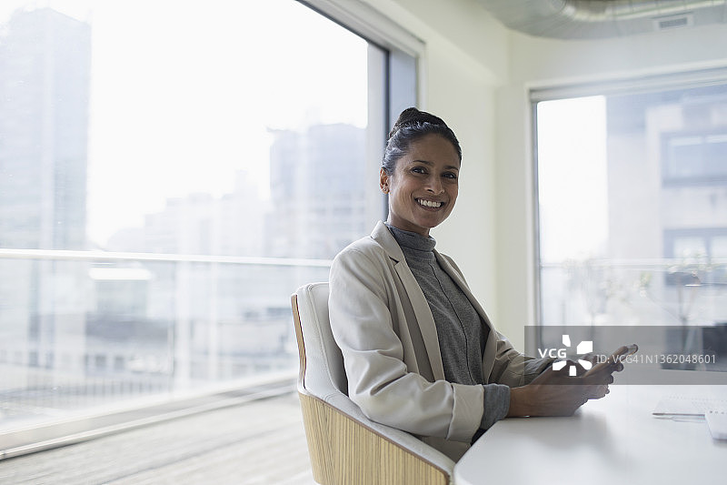 在会议室里拿着智能手机的快乐女商人肖像图片素材
