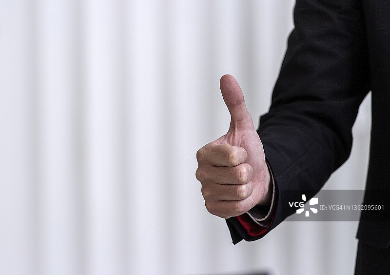 商人竖起大拇指，象征取得巨大成功图片素材